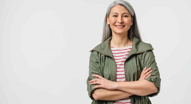 Una mujer mira de frente sonriendo y los brazos cruzados