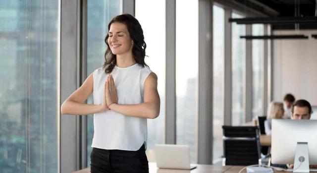 Mindfulness. Mujer sonriente haciendo yoga en la oficina
