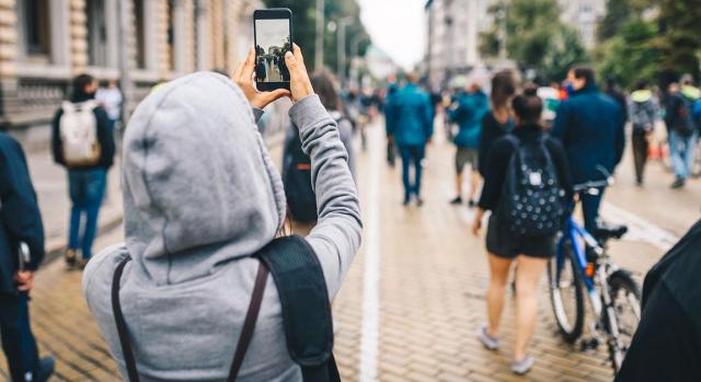 Despido disciplinario. Derecho a la intimidad y al secreto  de las comunicaciones. Imagen de mujer con capucha haciendo un video a la gente en la calle