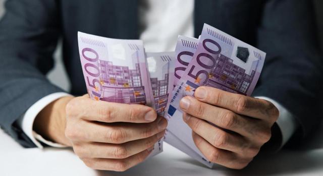 Reintegro de subvenciones. Imagen de primer plano de las manos de un hombre de negocios contando billetes de 500 euros