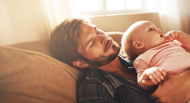 Padre dormido con el bebé en brazos