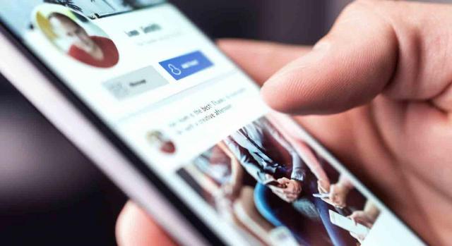 Despido procedente; abuso de confianza; Facebook. Primer plano de un móvil mostrando el perfil de una persona en las redes sociales