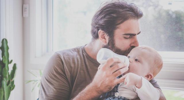 El permiso se configura como un derecho individual. Imagen de padre con bebé en brazos dándole de comer