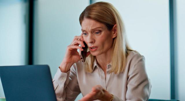 Hay que efectuar una interpretación con perspectiva de género. Imagen de mujer de aspecto preocupado hablando por teléfono sentada frente a portátil