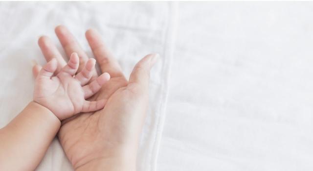 Superposición de palmas de manos de padre y bebé recien nacido en vínculo de paternidad