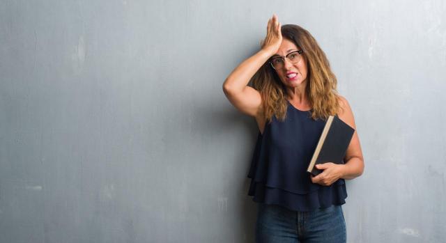 Mujer de pie sobre pared gris sosteniendo un libro de materia preventiva entre funcionarios