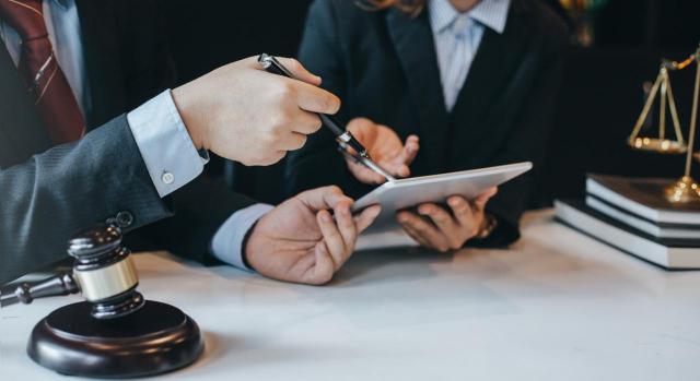 No hay litispendencia en el proceso de extinción del contrato vía artículo 50 del ET por estar pendiente de resolución un procedimiento de oficio sobre declaración de relación laboral. Imagen de unos abogados sentados en una mesa hablando sobre un caso