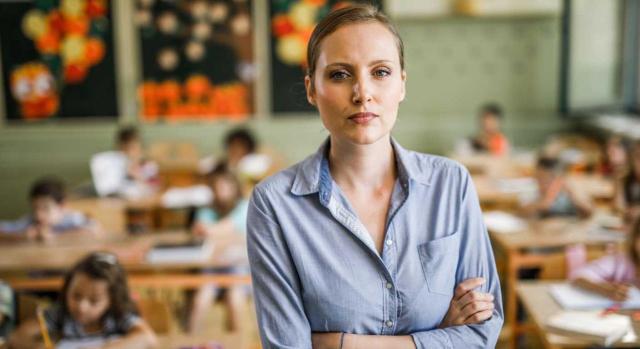 Prestación por desempleo. Incompatibilidad de la prestación con el trabajo de personal fijo discontinuo cuando reinicia su actividad, sin distinguir el tratamiento para trabajo a tiempo parcial o para uno a jornada completa No se puede compatibilizar la prestación por desempleo con el reinicio de la actividad fija discontinua al comenzar una nueva campaña, aun cuando se presten servicios a tiempo parcial. Imagen de una profesora joven muy serie y sus alumnos detrás en sus pupitres