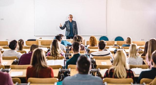 Profesor hablando con un grupo de estudiantes universitarios en un anfiteatro