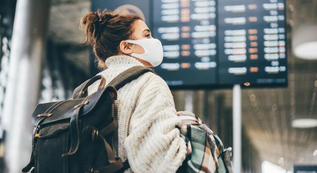 Prórroga hasta diciembre de la restricción temporal de viajes no imprescindibles desde terceros países a la UE por la COVID-19. Imagen de una mujer con mascarilla mirando las pantallas del aeropuerto