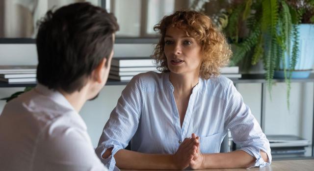 Reducción de jornada por guarda legal y concreción del horario. Un chico y una chica hablando en un escritorio de trabajo