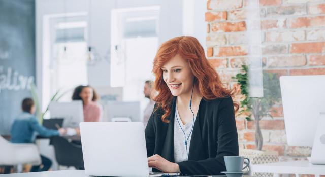 Se presume a jornada completa el trabajo a tiempo parcial desempeñado en empresa que no dispone de registro horario. Imagen de una chica en la oficina con su portátil muy sonriente