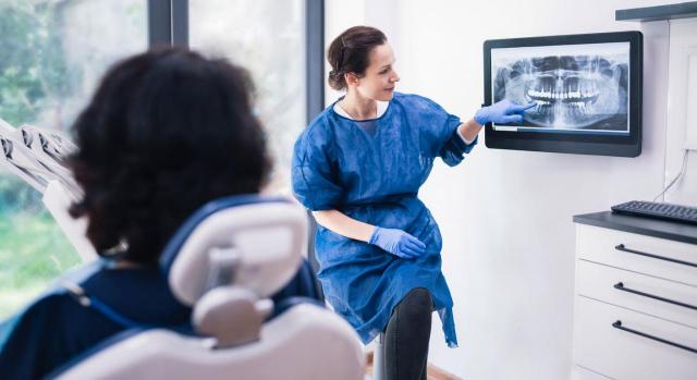 Accidente de trabajo en situación de pluriactividad. Presunción de laboralidad. Responsabilidad de las Mutuas respectivas. Imagen de una dentista explicando radiografías dentales a un paciente