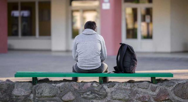 Salarios de tramitación a cargo del Estado. Se refieren exclusivamente al procedimiento de despido individual. Imagen de la espalda de un chico sentado frente al colegio