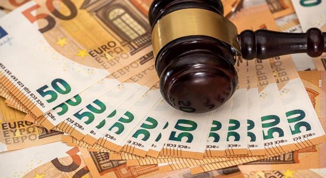 Reclamación al Estado de salarios de tramitación. Procesos acumulados de despido y extinción del contrato de trabajo al amparo del artículo 50 del ET Procesos acumulados de despido y extinción del contrato de trabajo al amparo del art. 50 del ET: aunque la sentencia estime ambas pretensiones ello no implica que se generen automáticamente salarios de tramitación. Imagen de un mazo de juez sobre muchos billetes de 50 euros