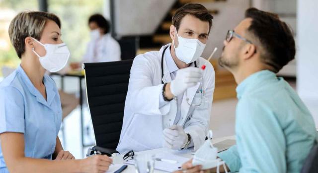 Mejoras voluntarias; incapacidad temporal; Covid-19. Dos sanitarios haciendo la prueba a un paciente en busca de coronavirus
