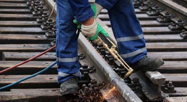 Trabajador soldando en una vía de tren. Sucesión de empresa