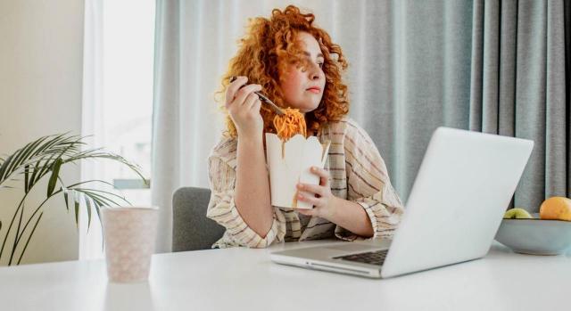 Se trataba de evitar que los trabajadores accedieran a restaurantes y cafeterías durante la pausa para la comida. Imagen de mujer teletrabajando y comiendo en su puesto de trabajo