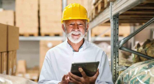 Jubilación activa; cierre del negocio; extinción del contrato Jubilación activa; cierre del negocio; extinción del contrato. Trabajador senior con una tablet en la mano y un casco amarillo