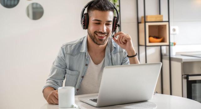 Demanda de despido interpuesta por un teletrabajador. Competencia territorial. Trabajador contratado por empresa con domicilio social en Canarias que presta servicios en Madrid Cese de teletrabajador. Puede presentar la demanda de despido ante el Juzgado de lo Social en cuya circunscripción se encuentre su domicilio, aunque sea otro el que figure en el contrato de trabajo. Imagen de un joven que trabaja como agente en el centro de llamadas desde casa mientras toma café