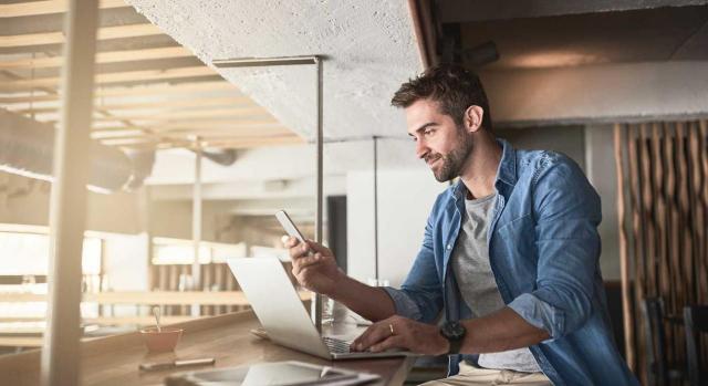 Utilización de las apps en las empresas Utilización de las apps en las empresas. Hombre en un cafetería frente a un portátil y un móvi
