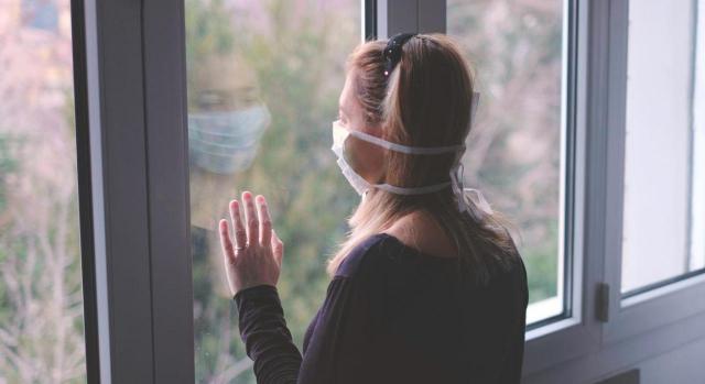 Procede la aplicación analógica del artículo 38.3 del TRET. Imagen de mujer con mascarilla mirando lejos por la ventana