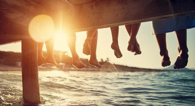 Las vacaciones mejoran la productividad. Personas sentadas sobre un muelle en el mar