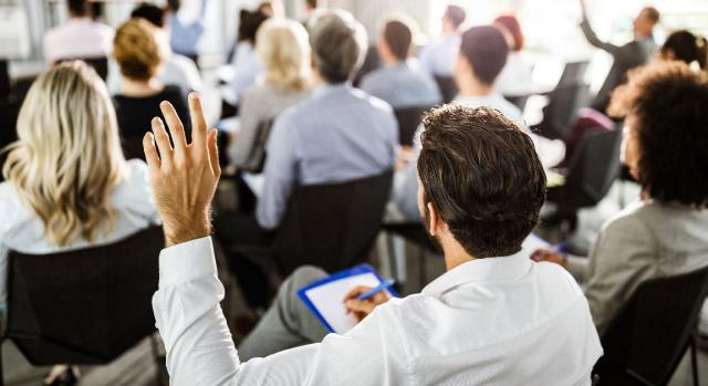 Empresario levantando la mano en un seminario para preguntar