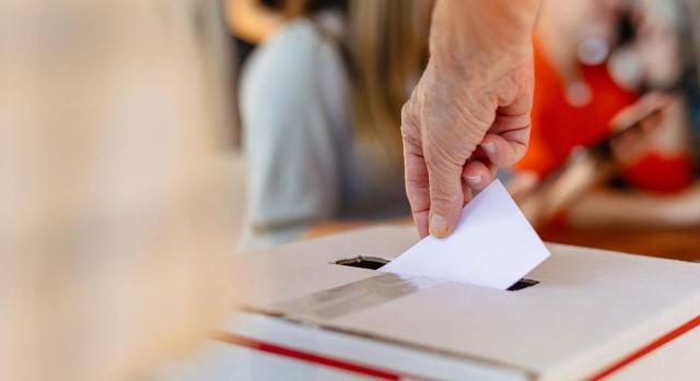 A efectos de solicitar retribución o descanso por el tiempo excedido. Mano colocando la papeleta en la urna de votación en la elección