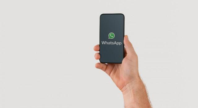 Imagen de mano sujetando un teléfono inteligente con el logotipo de WhatsAppup